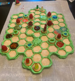 An image of an edible Melee board made from hexagon-shaped cookies, green, blue, and red icing, gummy bears and raspberries.